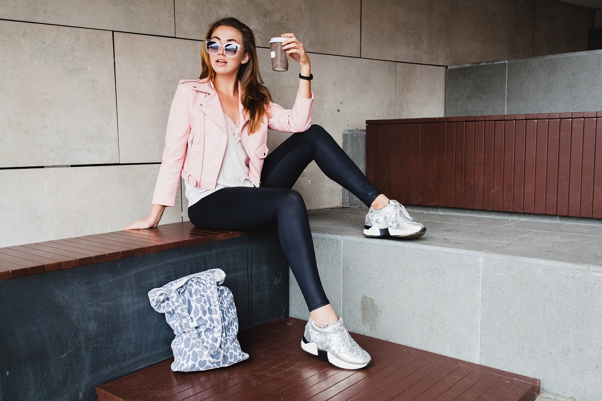 Mulher jovem sentada com oculos e tênis branco